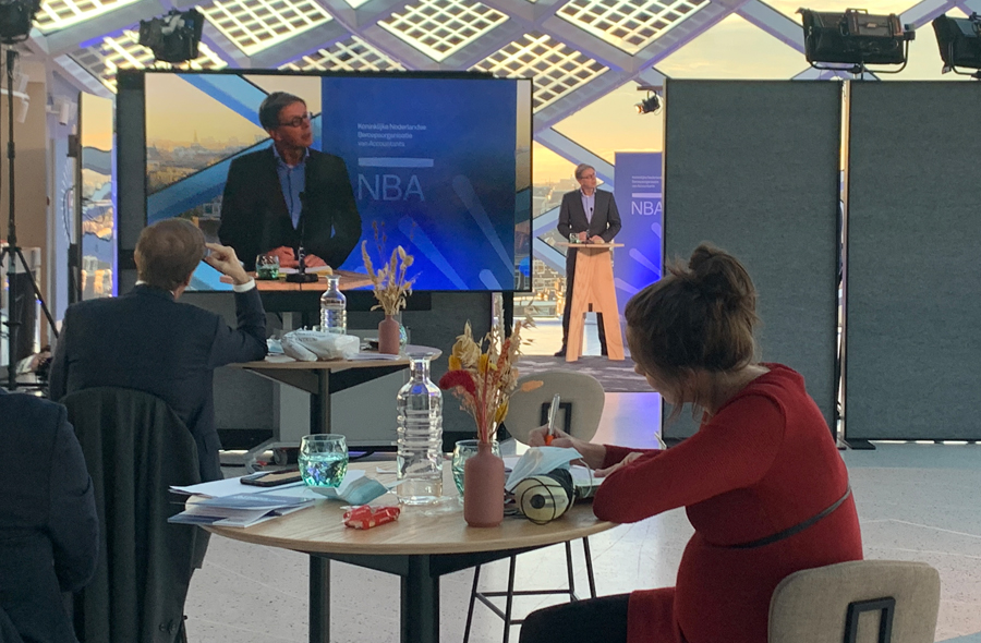 NBA-voorzitter Marco van der Vegte op het podium en op scherm tijdens the Future of Audit