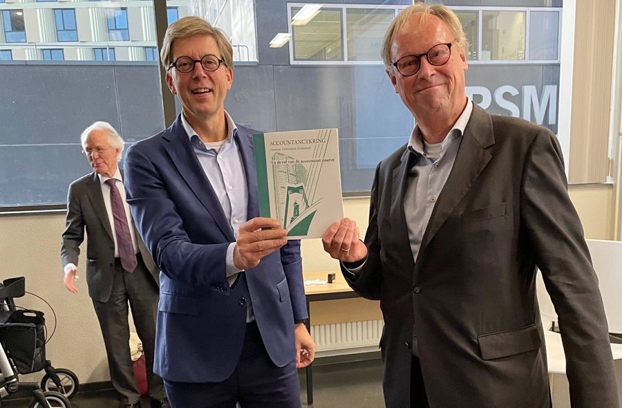 Hans van der Vlies overhandigt het eerste exemplaar van een boekje over de historie van de Accountancykring Erasmus Universiteit Rotterdam aan NBA-voorzitter Marco van der Vegte